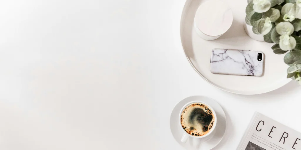 A clean workspace with a smartphone, coffee, and notebook, representing organisation, communication, and everyday support.
